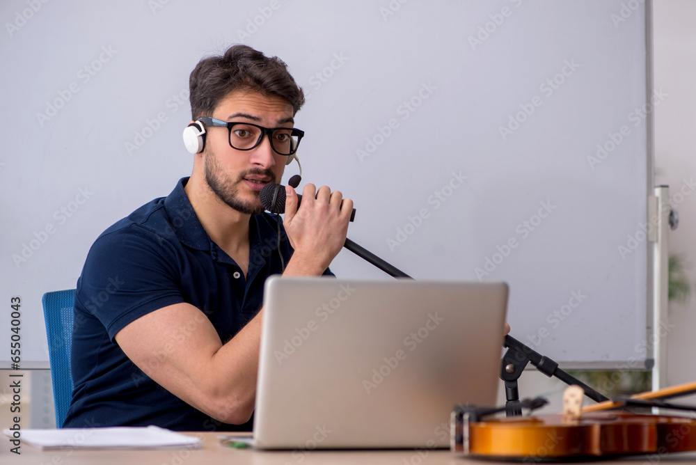 Young male music teacher sitting in the classroom Young male music teacher sitting in the classroom