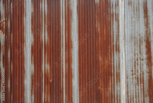 An old rusty metal sheet roof textured. Rust is an iron oxide formed by the reaction of iron and oxygen in the catalytic presence of water or air moisture. photo