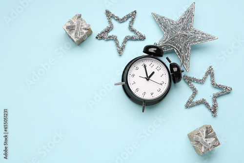 Composition with alarm clock, Christmas decorations and gift boxes on color background photo