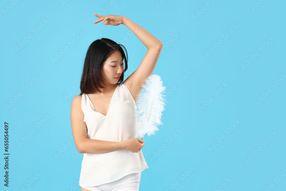 Young Asian woman with feather on blue background Young Asian woman with feather on blue background
