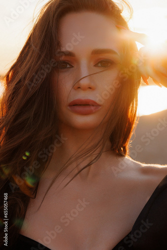 Portrait of a beautiful Caucasian brunette woman at sunset. The wind in your hair and the rays of the sun.