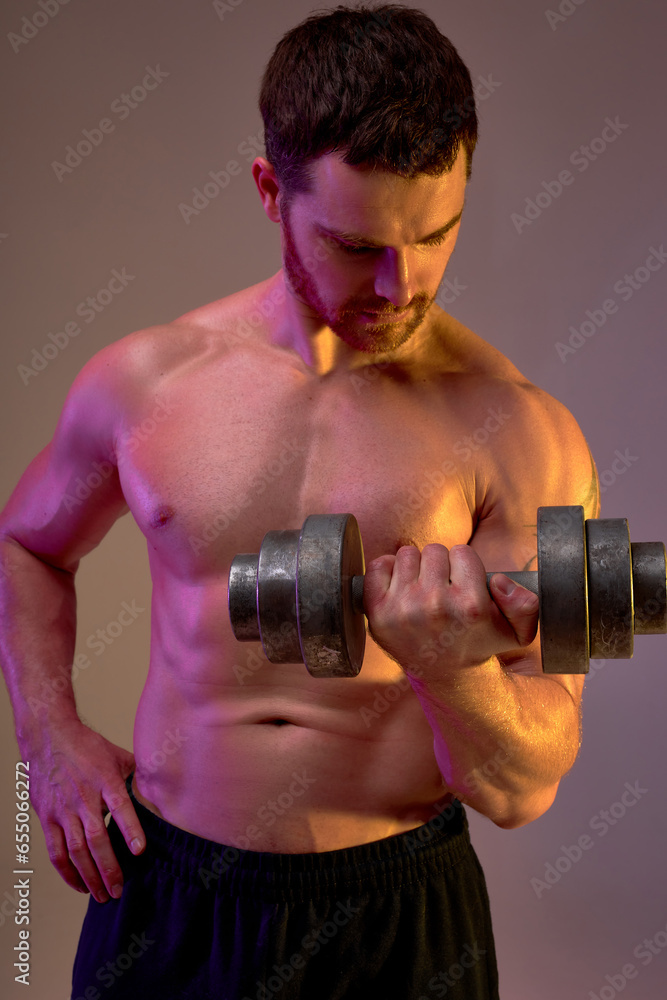serious handsome man in black shorts concentrated on weightlifting workout, effort. isolated brown background, wellness. health and body care
