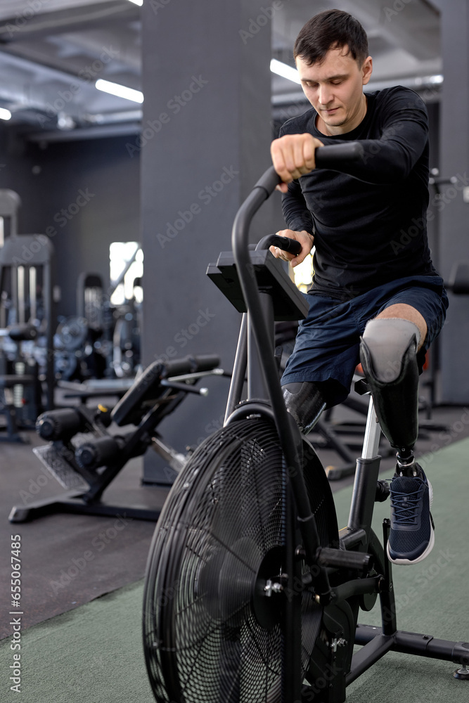 active man concentrated on working out on a stationary bike. A man is engaged in sports in the gym. full length shot. motivation, strength training active man concentrated on working out on a stationary bike. A man is engaged in sports in the gym. full length shot. motivation, strength training
