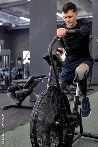 active man concentrated on working out on a stationary bike. A man is engaged in sports in the gym. full length shot. motivation, strength training