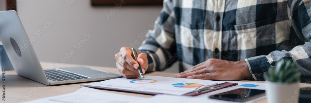 Startup businessman read marketing graph document and thinking about strategy of business project Startup businessman read marketing graph document and thinking about strategy of business project