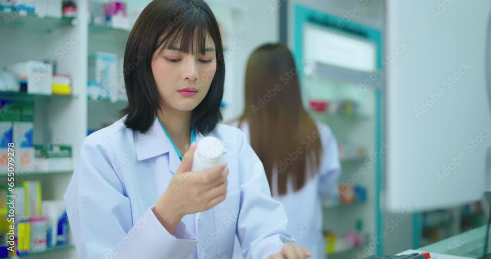 Young asian female pharmacist using computer in pharmacy shop. She research drug information at pharmacy shop.