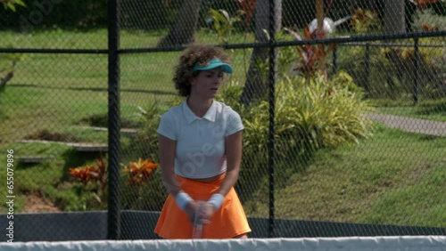 Young woman in orange skirt and white t-shirt playing lawn tennis on tennis court, active lifestule concept, copy space, high quality photo