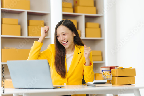 Asian china people entrepreneur in yellow suit diligently packing products into boxes. modern SME scene, she processes orders received via live stream platforms, e-commerce revolution.