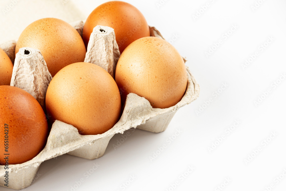 A tray of brown fresh hens eggs on white background. Eco-friendly egg production. Baking ingredients. Organic chicken eggs - fresh from producer. Top view. A tray of brown fresh hens eggs on white background. Eco-friendly egg production. Baking ingredients. Organic chicken eggs - fresh from producer. Top view.