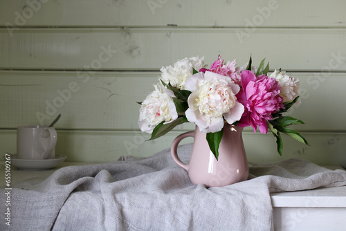 Fototapeta Naklejka Na Ścianę i Meble -  bouquet of pink and white peonies on a table in a wooden house.