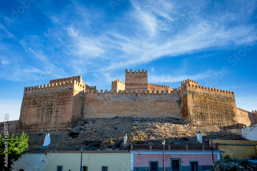 Crenellated walls of the Guadix citadel, Granada, Andalusia, Spain, with cave houses below photo