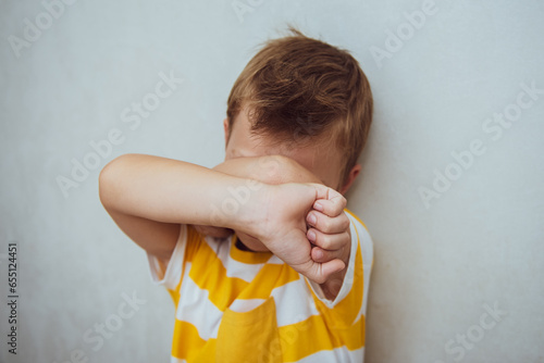 Little sad child kid boy 6-7 years old wear casual clothes cover face with hands cry isolated on gray background studio portrait. Mother's Day love family lifestyle concept photo