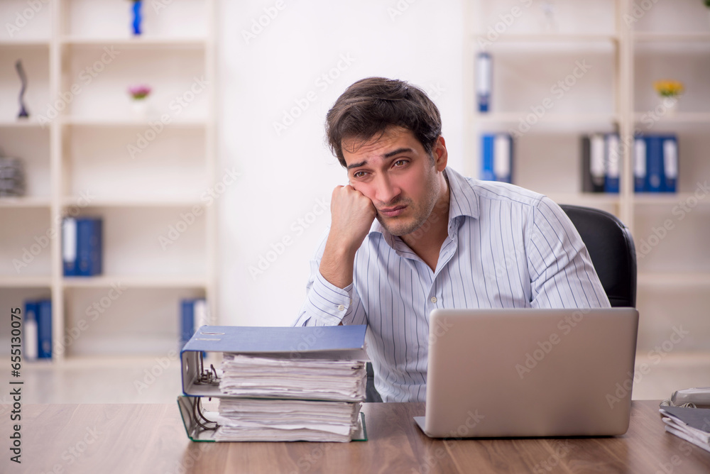 Young male employee and too much work in the office Young male employee and too much work in the office