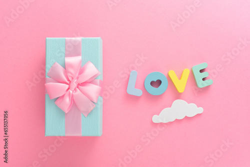 Gift box and letter LOVE on a pink background
