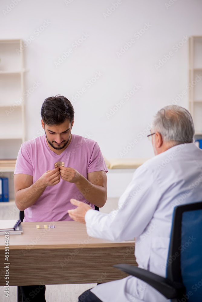 Obraz premium Young male patient visiting old male doctor