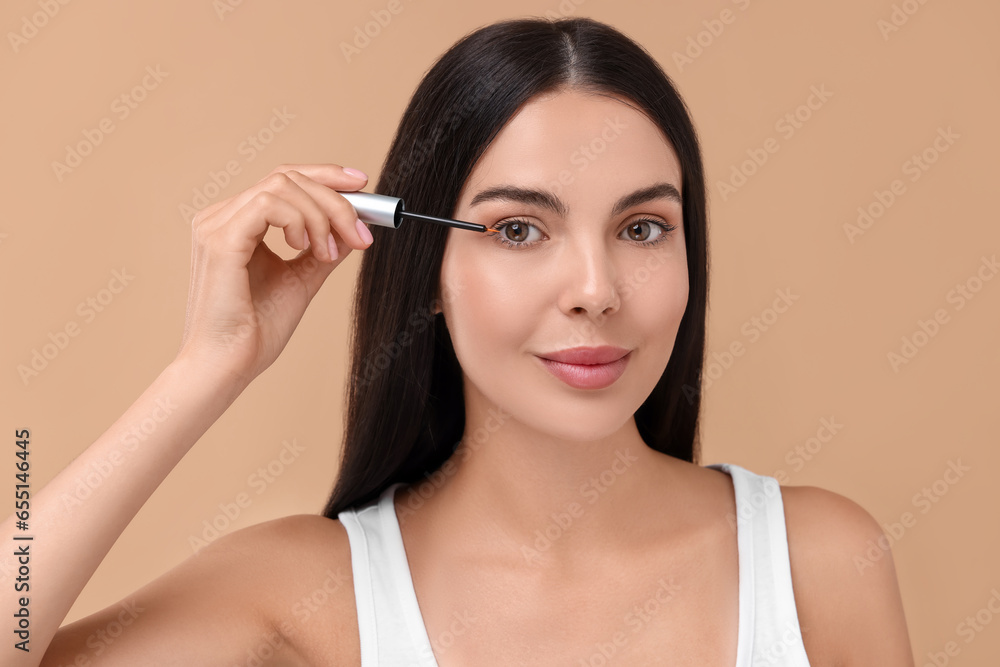 Beautiful woman applying serum onto her eyelashes on beige background. Cosmetic product Beautiful woman applying serum onto her eyelashes on beige background. Cosmetic product