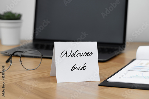 Paper note with phrase Welcome Back on office desk photo