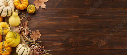 Creating a Thanksgiving mood. Top view composition of vibrant pumpkins, warm blanket, traditional fall elements on wooden background with advertisement area