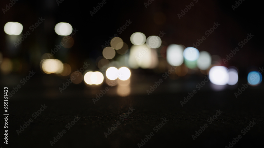 Low angle bokeh background of night city with car light passing by - obrazy, fototapety, plakaty 