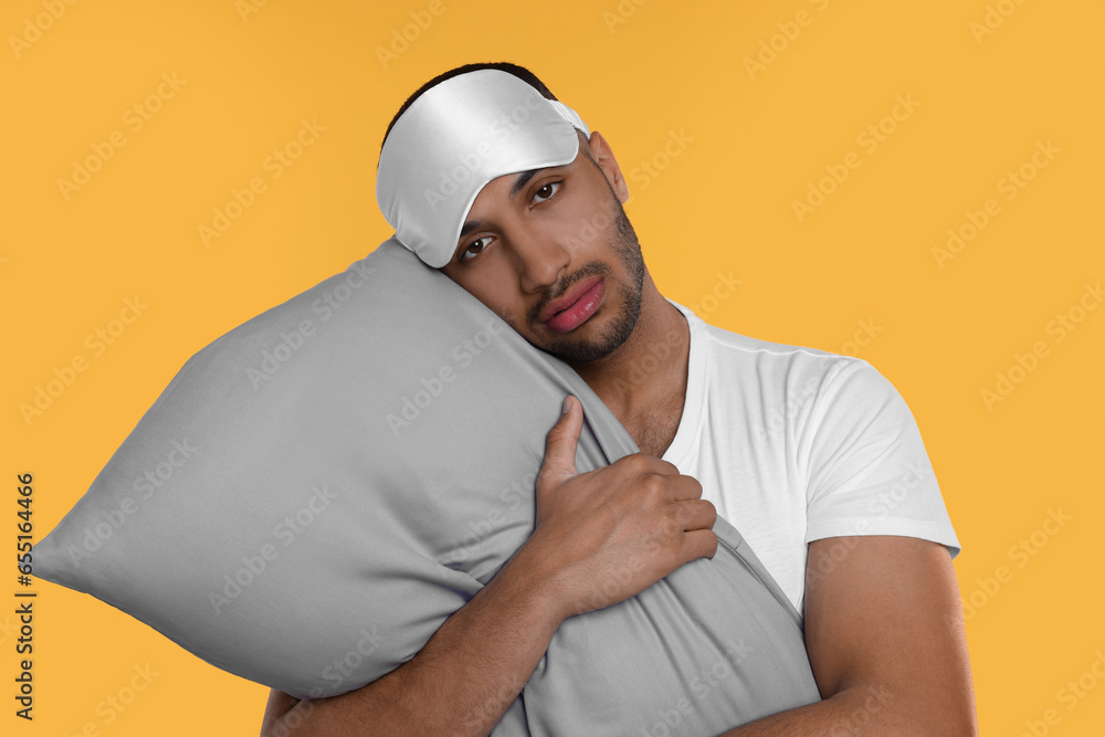 Tired man with pillow and sleep mask on orange background. Insomnia problem Tired man with pillow and sleep mask on orange background. Insomnia problem