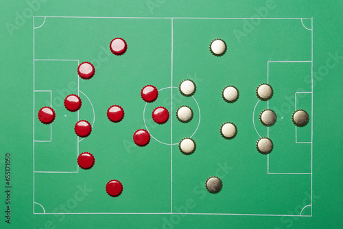 Football soccer game play tactic strategy scheme plan formation made of golden and red beer bottle caps on the bright solid fond plain green field background