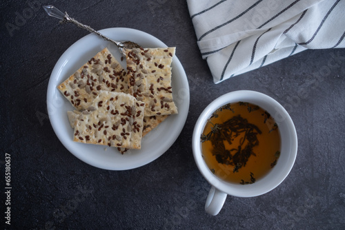 a cup of tea is on the table, and there are cookies in a saucer next to it. Sugar is on the table. Breakfast. tinting