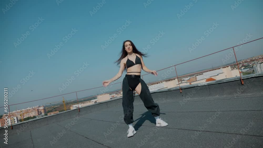 A girl in a swimsuit dances sexy on the roof. booty dance, booty shake