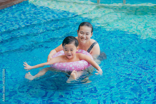 Happy Asian mother and son posing at swimming pool