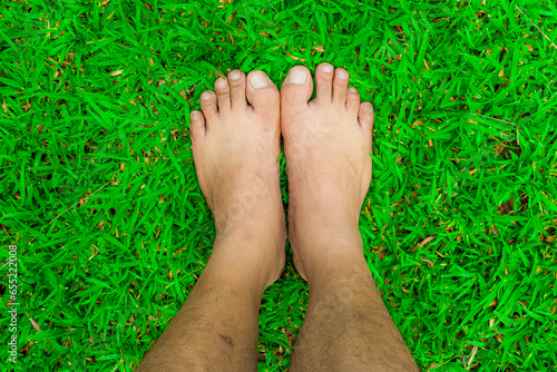 A person's feet stand on the green grass. © sorrawit
