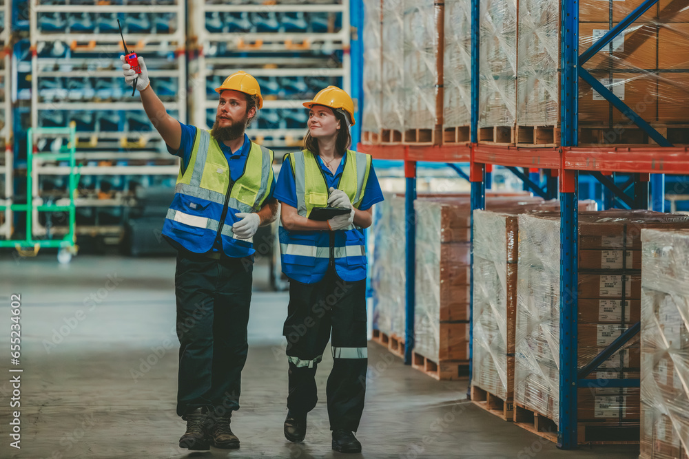 Fototapeta premium Warehouse staff verify automotive, paper items using handheld device, ensuring precise shipment.