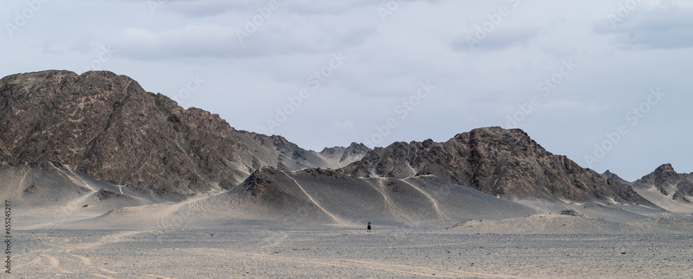 A woman walking in front of a huge black mountain.