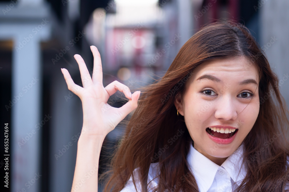 Happy smiling friendly Chinese asian woman office worker pointing approving ok, okay, all correct hand gesture