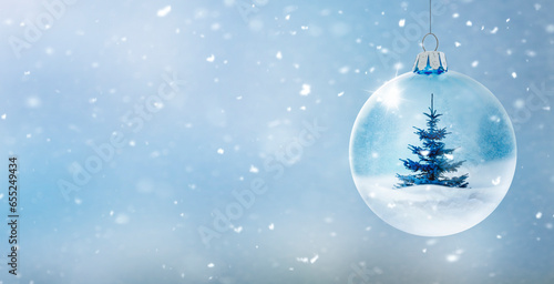 Transparente Glaskugel vor unscharfem Winterhintergrund mit Schneeflocken