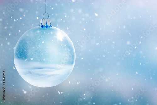 Transparente Glaskugel vor unscharfem Winterhintergrund mit Schneeflocken