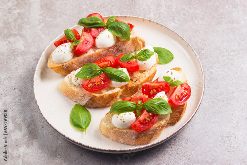Tomato, basil and mozzarella cheese fresh made caprese bruschetta. Italian tapas, antipasti with vegetables, herbs and oil on grilled ciabatta and baguette bread. Open sandwich.