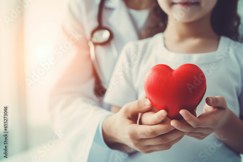 Child and adult holding a red heart with stethoscope photo