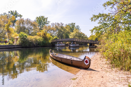 voyaguer canoe on shore with a wooden bridge in background shot on the toronto islands in autumn