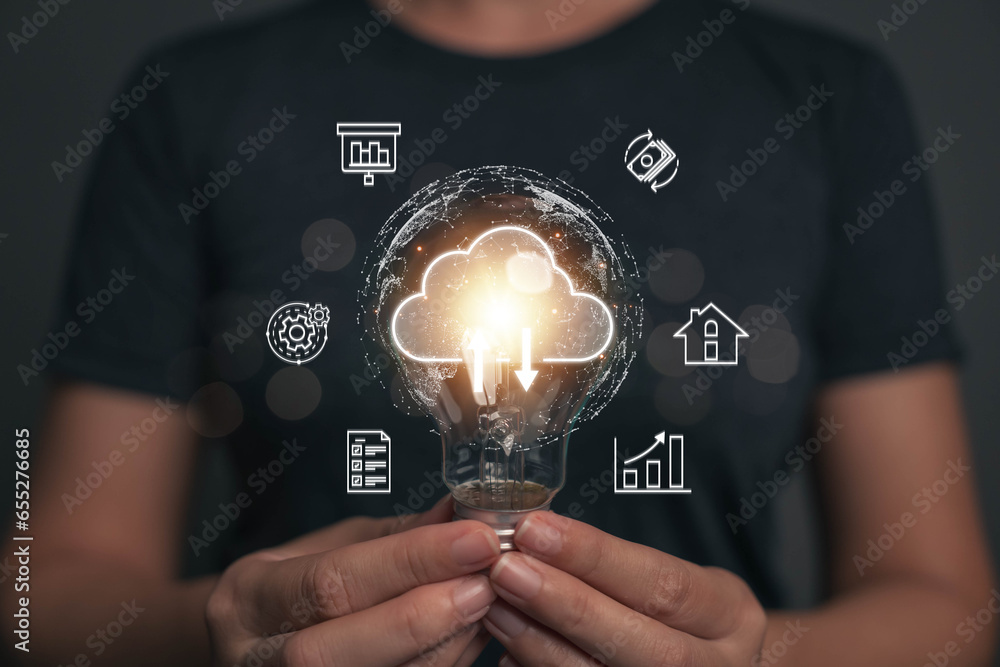 A light bulb that shines in the hand of a businessman. One idea for transmitting business information using cloud technology. Ideas from searching for economic data for marketing. - obrazy, fototapety, plakaty 