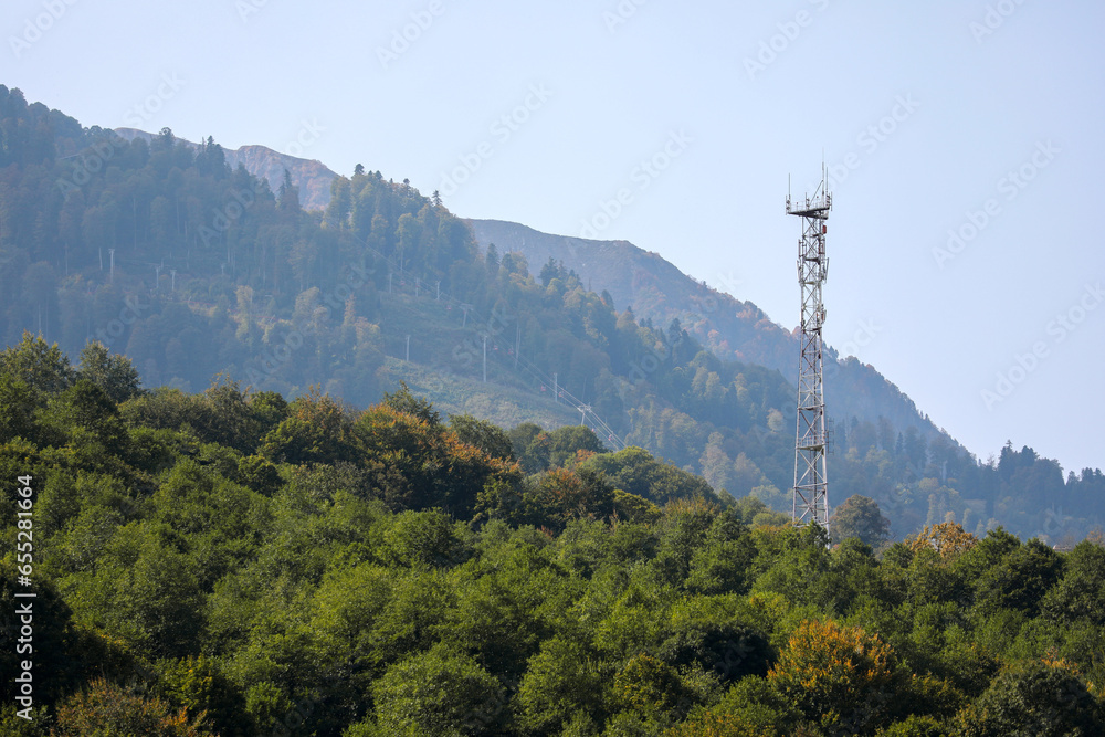 Obraz premium Metal structure, communication tower in a mountainous area, against the background of high mountain peaks. Russia, Krasnaya Polyana, Sochi.