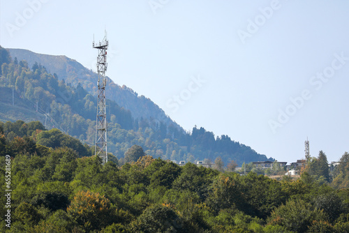 Metal structure, communication tower in a mountainous area, against the background of high mountain peaks. Russia, Krasnaya Polyana, Sochi.