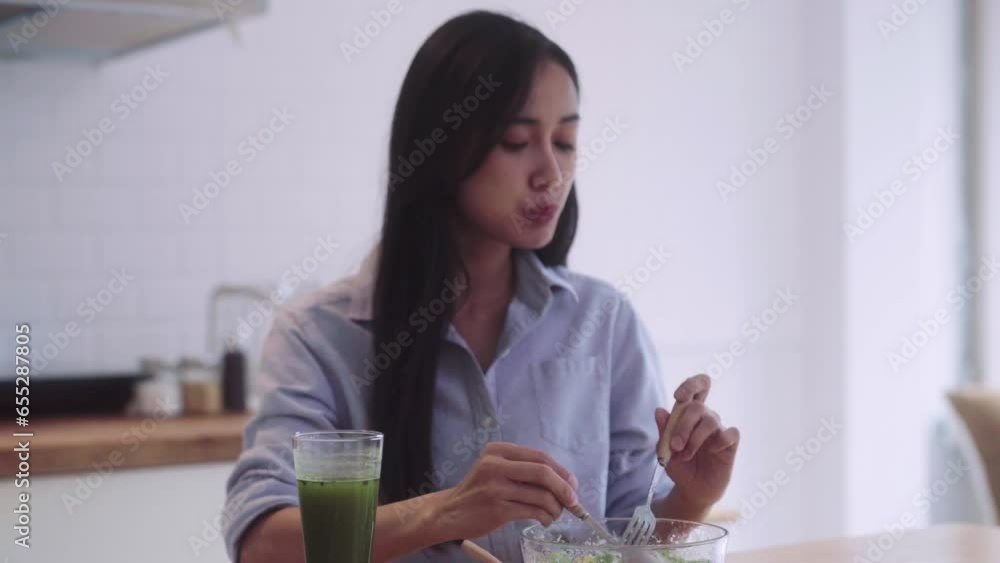 Young Healthy Asian woman eating lettuce salad and enjoy eat clean vegetables in kitchen at home. Weight loss and lifestyle concept Young Healthy Asian woman eating lettuce salad and enjoy eat clean vegetables in kitchen at home. Weight loss and lifestyle concept