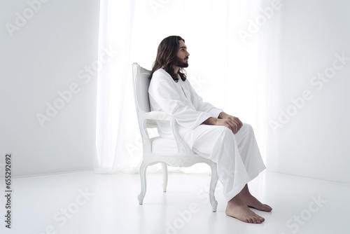 Side view of a man with long hair and beard siitting in an all white room with soft white bright light photo
