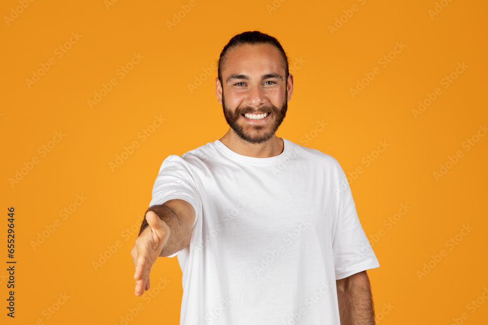 Smiling friendly adult european guy with beard in white t-shirt gives hand for shake - obrazy, fototapety, plakaty 