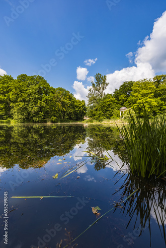 Beautiful and colorful park at sunny morning with blue sky with few clouds beautifully reflecting in big silent lake like in mirror photo