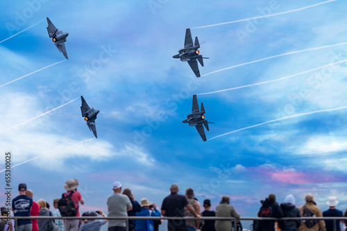 Fighter jets flying over spectators on a pier  