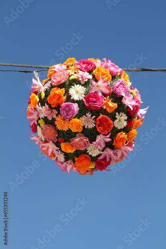 Kugel aus frischen Sommerblumen aufgehängt als Dekoration vor blauem Himmel 