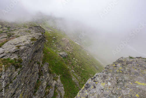 steep slopes of fagaras mountains, romania. rocks and boulders among the grass. foggy weather. mysterious adventures