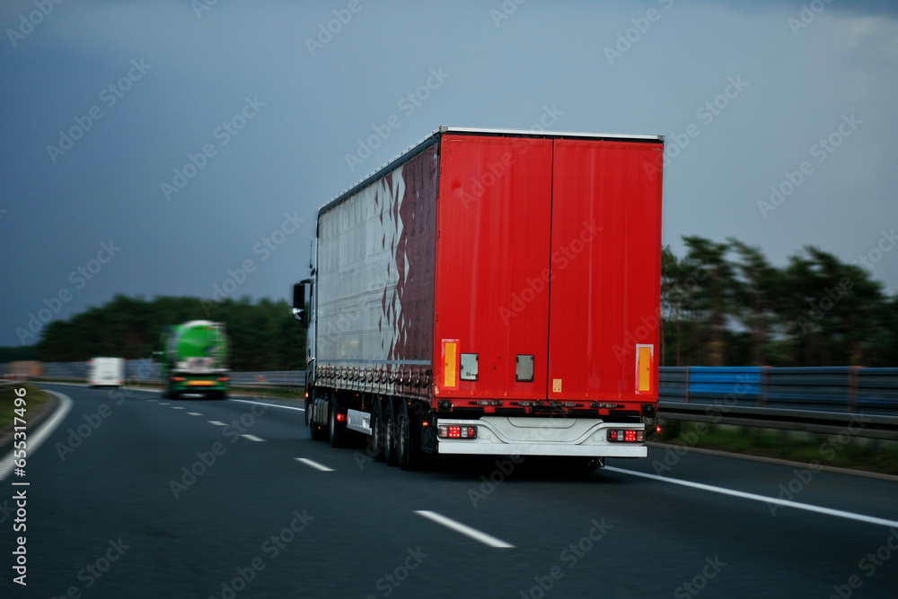 Modern semi-trailer trucks on the highway driving in the right lane. Commercial vehicle for shipping and post delivery. Shipping of the goods on land door-to-door