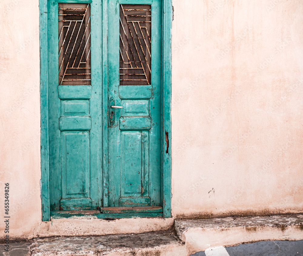old wooden blue green painted greek door with key in the lock, whitewashed building, traditional steet in Greek islands, cyclades