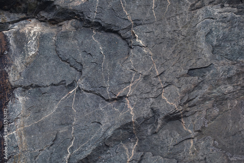 фотографія The output of dark shale rock with veins, natural stone background